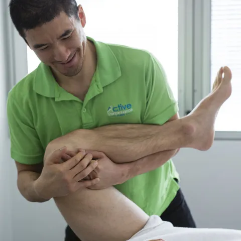 Practitioner mobilising a client's hip and leg during sports injury treatment